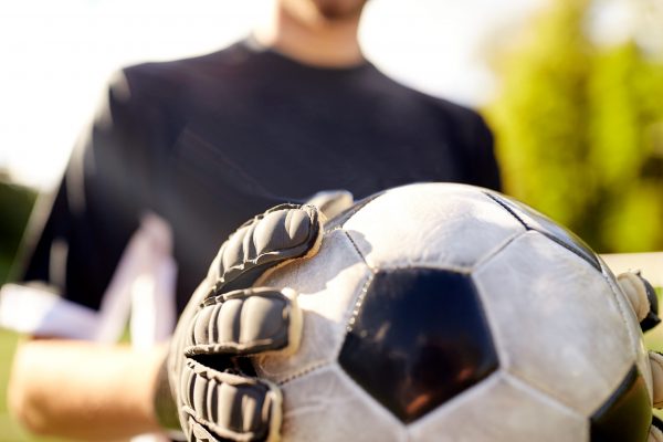 sport and people - close up of soccer player or goalkeeper holding ball at football goal on field